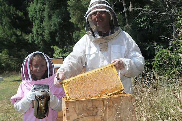 Mirboo North beekeeper Peter Gatehouse teaching his granddaughter Ruby Cautrier how to care for hives. photograph michelle slater